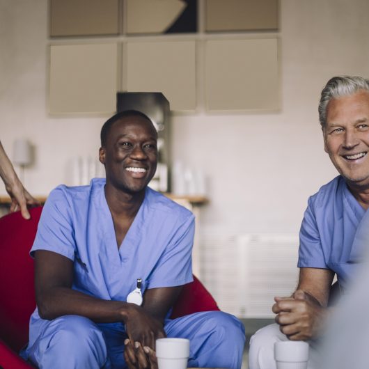 Vikarer i helsesektoren tar en kaffepause og smiler sammen på personalrommet.